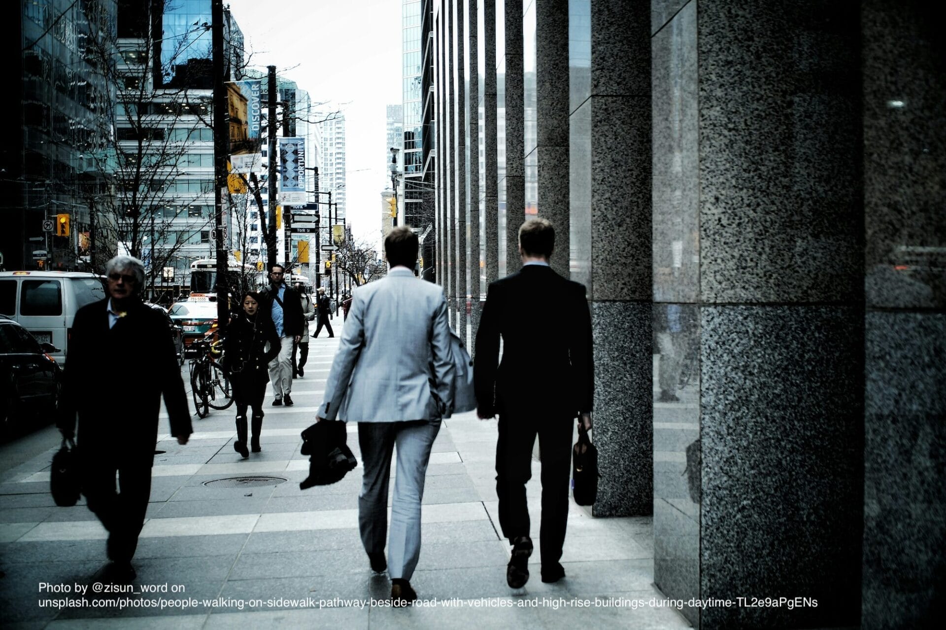 people-walking-on-sidewalk-pathway-beside-road-with-vehicles-and-high-rise-buildings-during-daytime